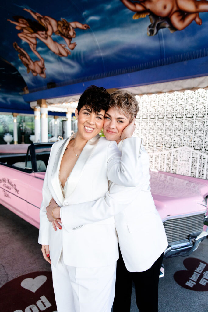 Couple posing with the Pink Cadillac at Little White Wedding Chapel