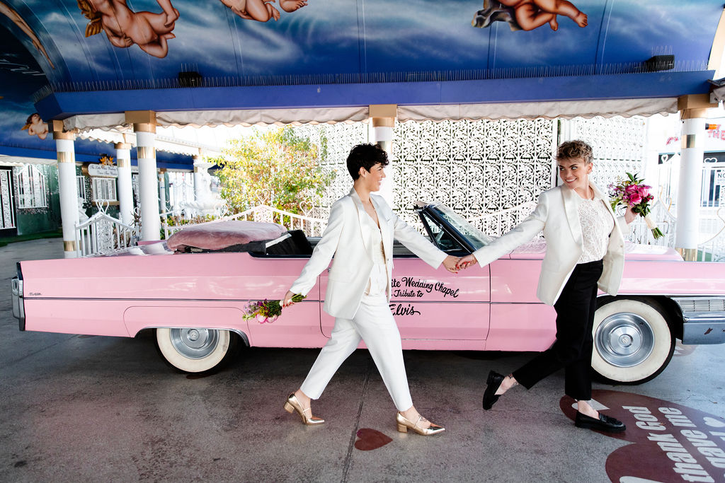 LGBTQ+ couple posing alongside the pink Cadillac for their Las Vegas wedding photos