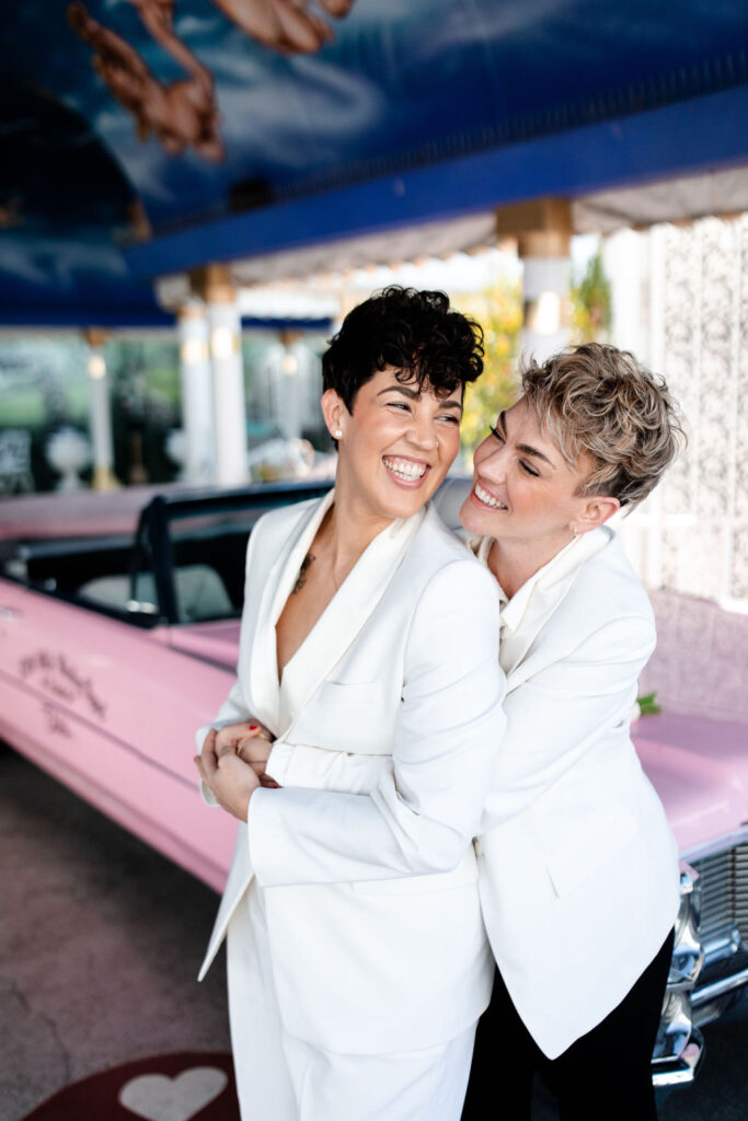 Couple posing with the Pink Cadillac at Little White Wedding Chapel