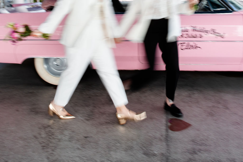 Couple walking alongside the Pink Cadillac for their Las Vegas wedding photos