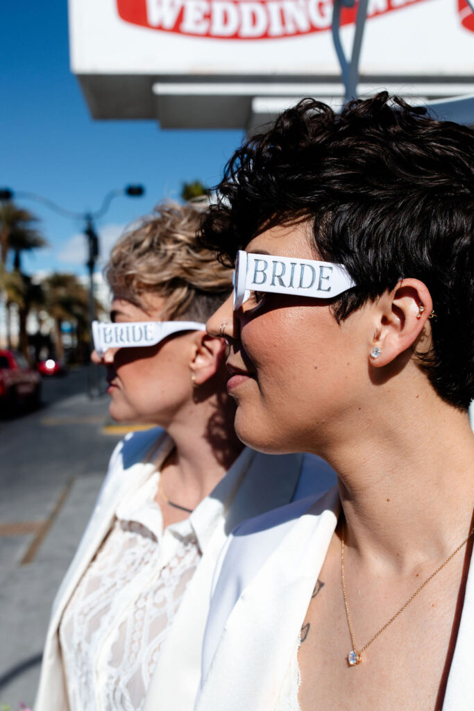LGBTQ+ couple wearing sunglasses that each say bride for their Las Vegas wedding photos