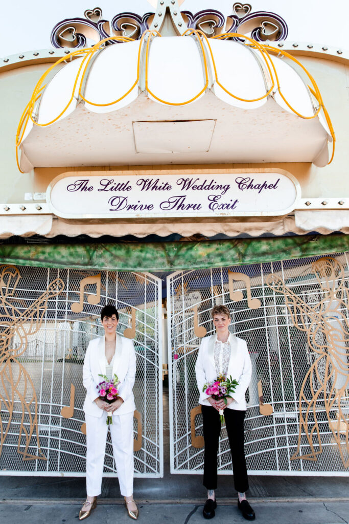 LGBTQ+ couple posing outside of Little White Wedding Chapels drive-thru-exit