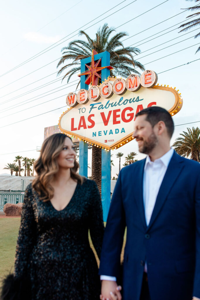 Couple holding hands in front of the Welcome to Fabulous Las Vegas sign