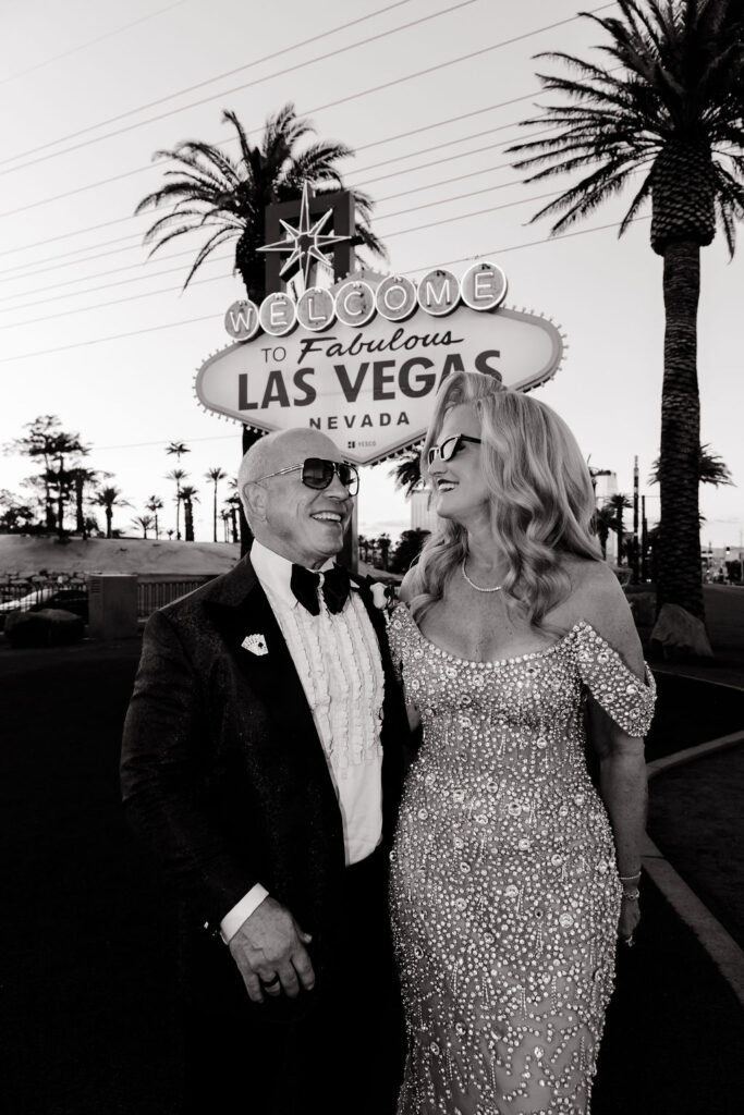 Black and white photo of a bride and groom posing in front of the Welcome to Fabulous Las Vegas sign