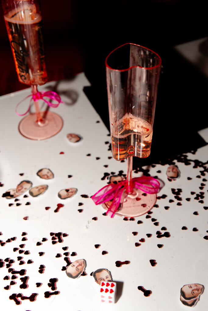 Playful Lucky in Love party details with heart confetti, custom face stickers, and themed champagne glasses