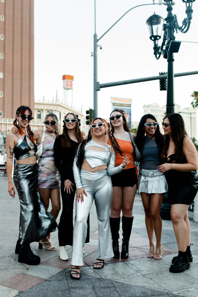 Group of women at a Las Vegas bachelorette party wearing metallic and futuristic outfits, posing in downtown Las Vegas