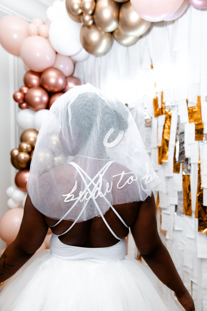 Bride wearing a short white dress and veil that says "bride to be"