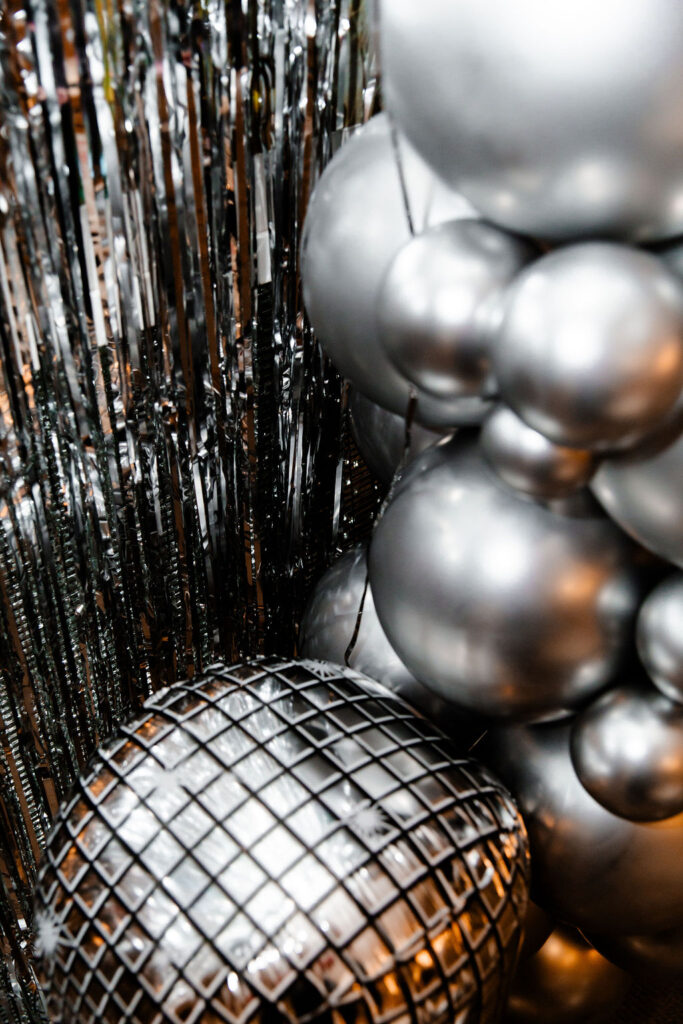 Last Disco photo backdrop with silver tinsel, balloons, and disco ball balloons 