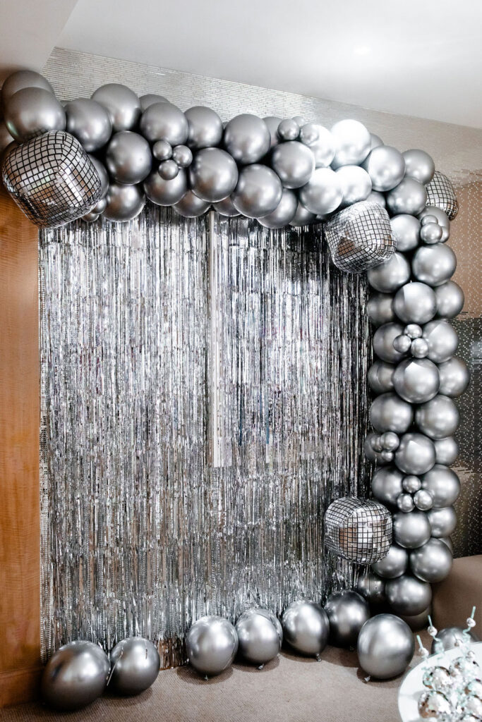 Last Disco photo backdrop with silver tinsel, balloons, and disco ball balloons 