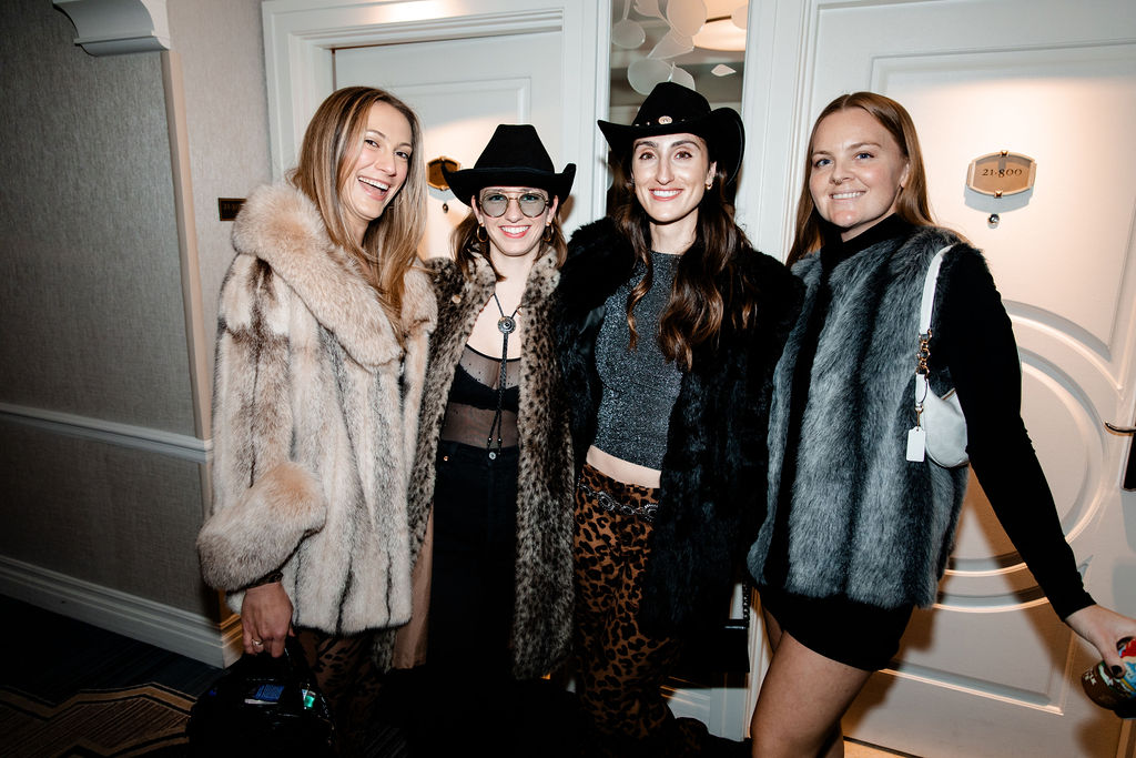 Bachelorette party guests in faux fur coats and cowgirl hats dressed for a western-themed night out in Las Vegas.