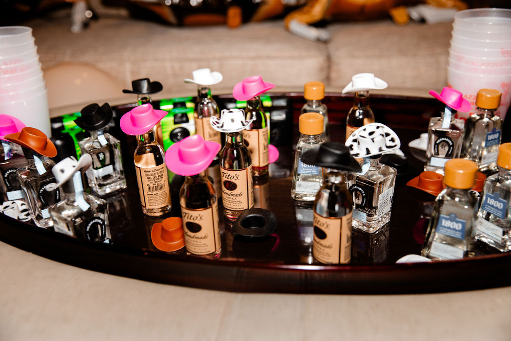 Mini tequila and vodka bottles topped with tiny cowboy hats for a western-inspired bachelorette party in Las Vegas