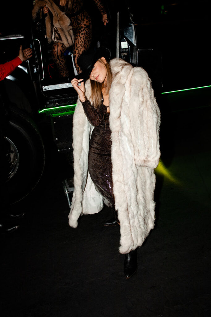 Bachelorette guest in a long sequin gown and glamorous fur coat with cowboy hat for a western theme night in Las Vegas