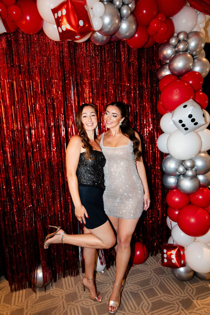 Bride in a silver mini dress with her friend in a sparkly black top, celebrating a Lucky in Love bachelorette party in Las Vegas
