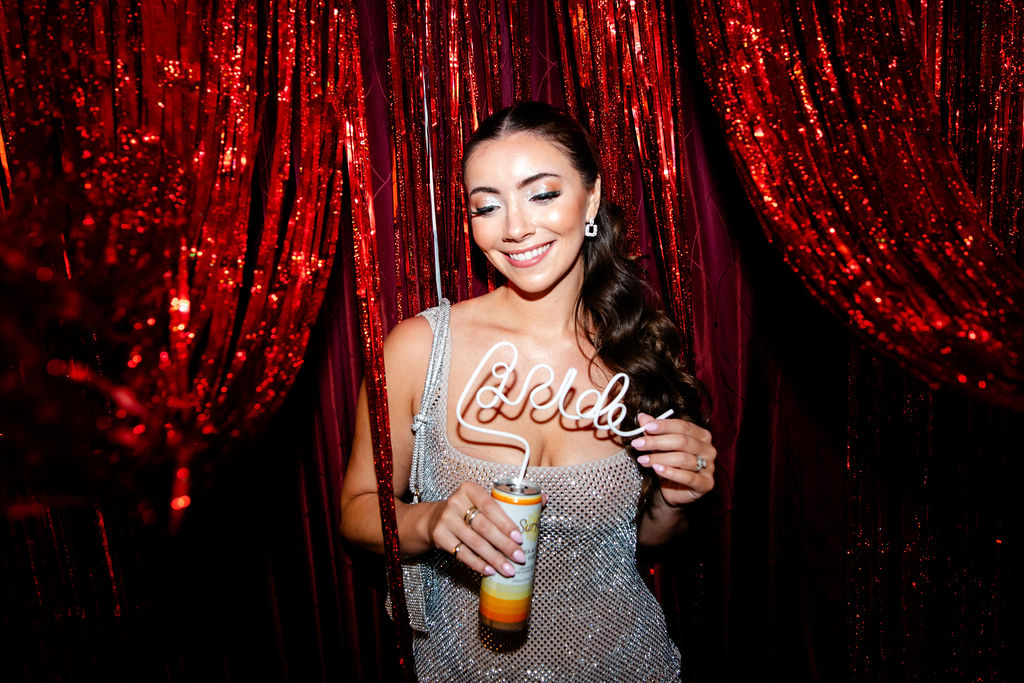 Bride smiling while holding a custom curly straw that spells ‘bride’ at her Lucky in Love bachelorette party in Las Vegas