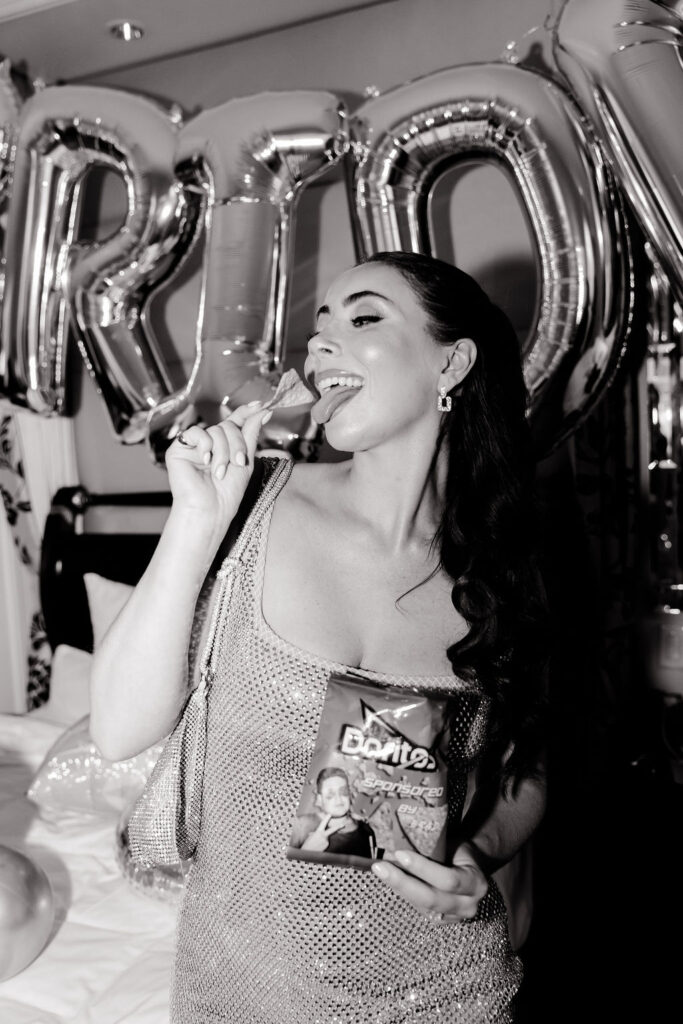 Bride laughing and eating from custom Doritos bag featuring groom’s face at a Lucky in Love bachelorette party in Las Vegas