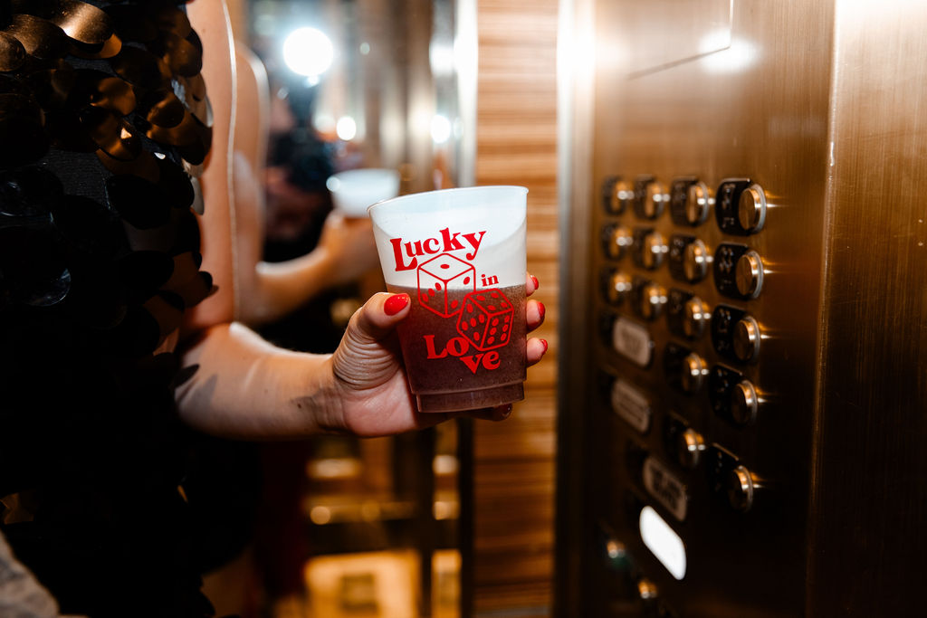 Close-up of custom ‘Lucky in Love’ cup with dice design inside a Las Vegas hotel elevator during a bachelorette party