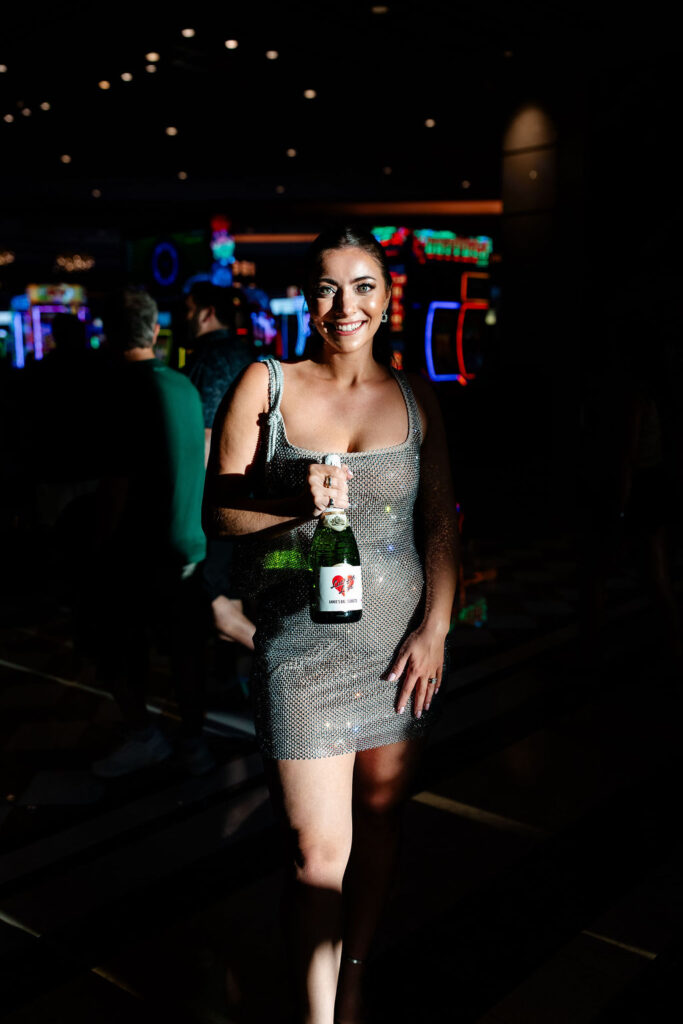 Bride posing in a casino with a custom bottle of champagne from her Las Vegas bachelorette party
