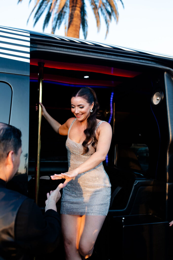 Bride in sparkly silver mini dress stepping out of the limo with a big smile