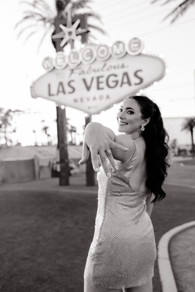 Bride smiling and holding out her engagement ring in front of the Welcome to Fabulous Las Vegas sign