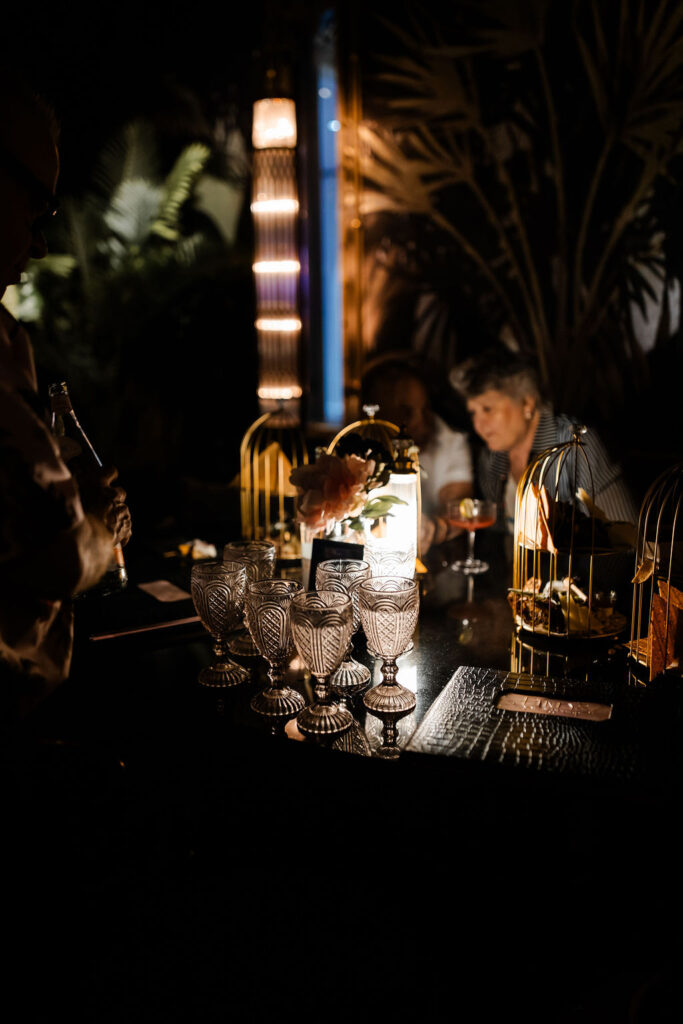 Moody photo of crystal glasses and charcuterie table setup at Pinky’s Vanderpump Las Vegas wedding reception.