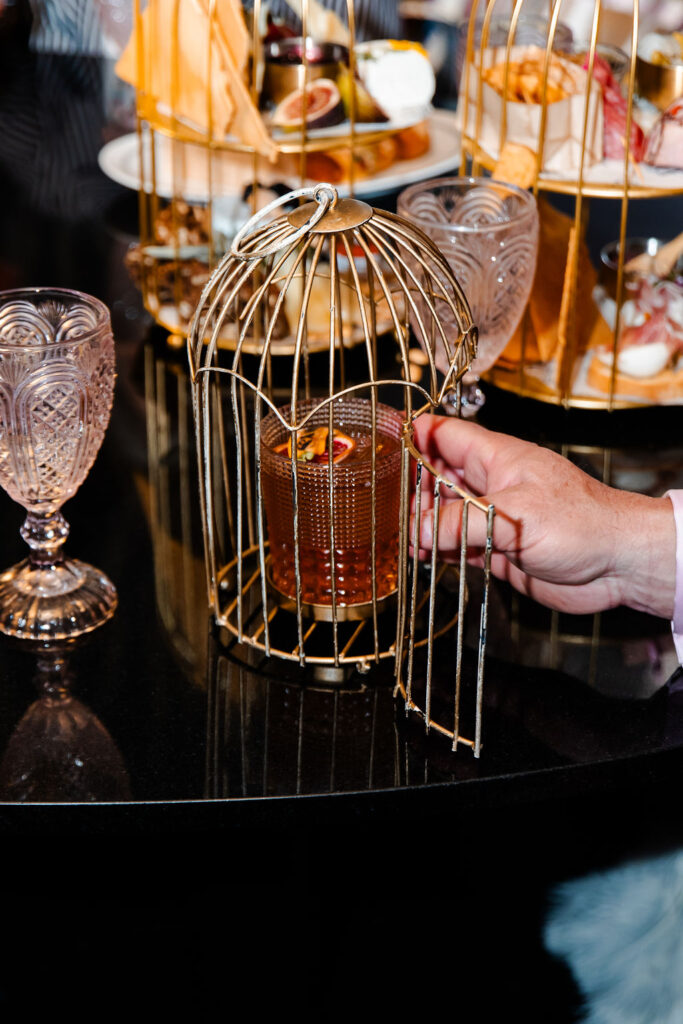 Creative cocktail served in a glass birdcage centerpiece at Pinky’s Vanderpump Las Vegas wedding reception.