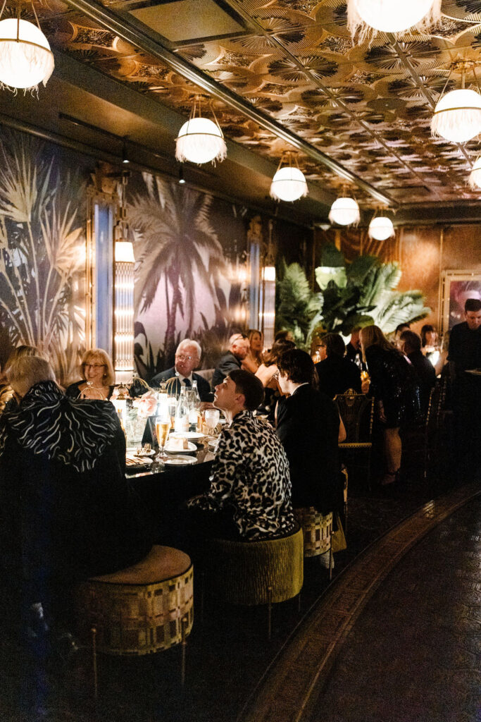 Guests seated at long dinner tables surrounded by tropical-inspired decor at Pinky’s Vanderpump Las Vegas wedding reception.