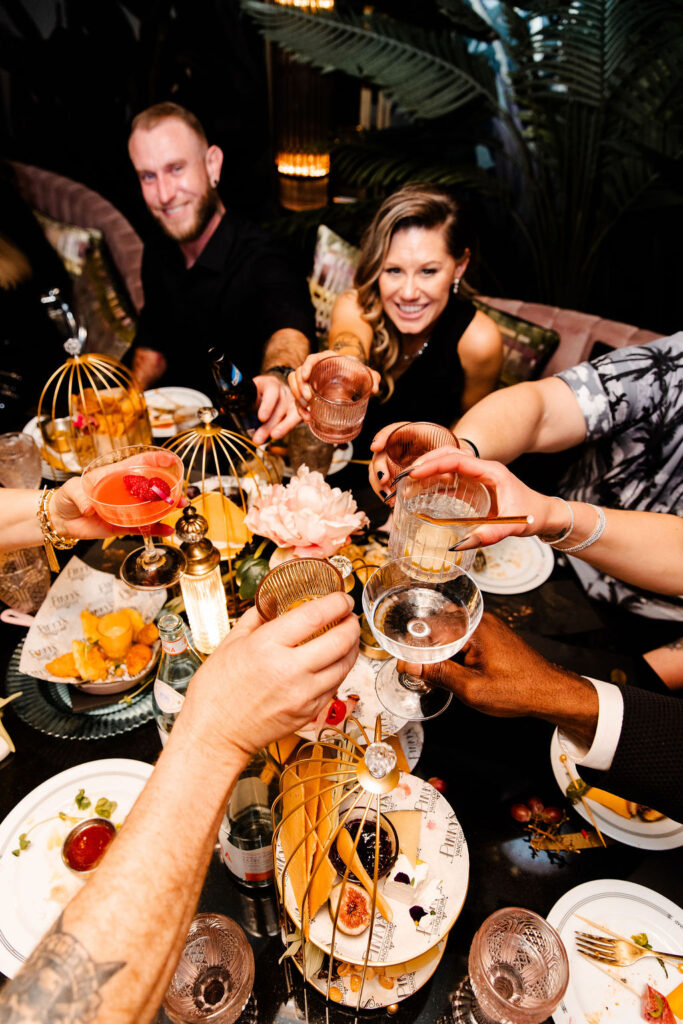 Group cheers with cocktails over charcuterie spread at Pinky’s Vanderpump Las Vegas wedding reception.
