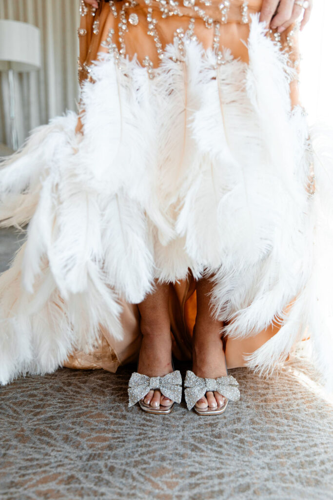 Glittery bow heels peek out from beneath the feather train of a crystal gown at Waldorf Astoria Las Vegas