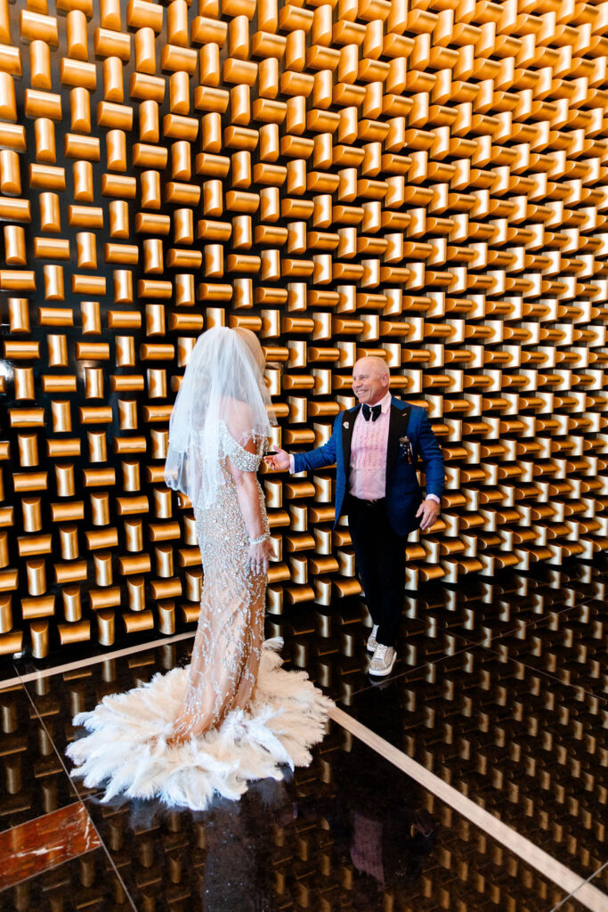 A groom smiles as he turns to see the bride in a sparkling gown during their wedding day first look at Waldorf Astoria Las Vegas