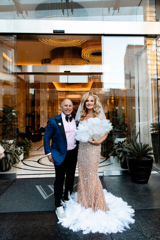 A couple poses hand in hand outside the Waldorf Astoria doors before their Las Vegas wedding celebration