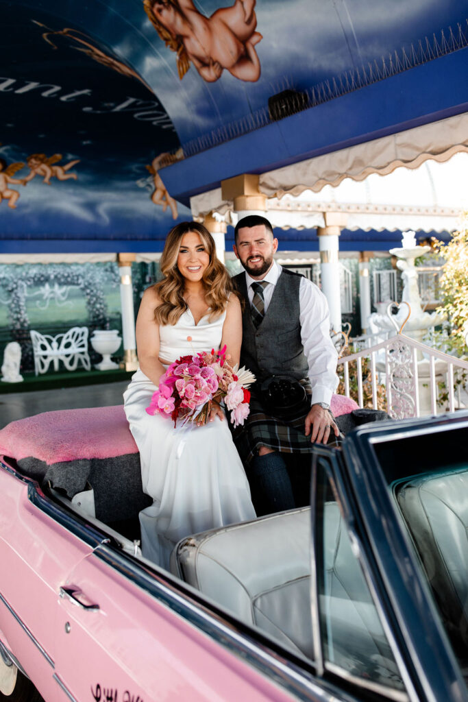 Couple posing for their Las Vegas elopement photos in the Pink Cadillac at The Little White Wedding Chapel in Las Vegas