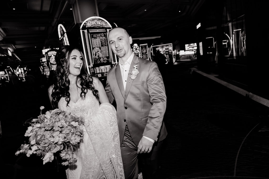 Black and white photo of a bride and groom walking through the Bellagio casino