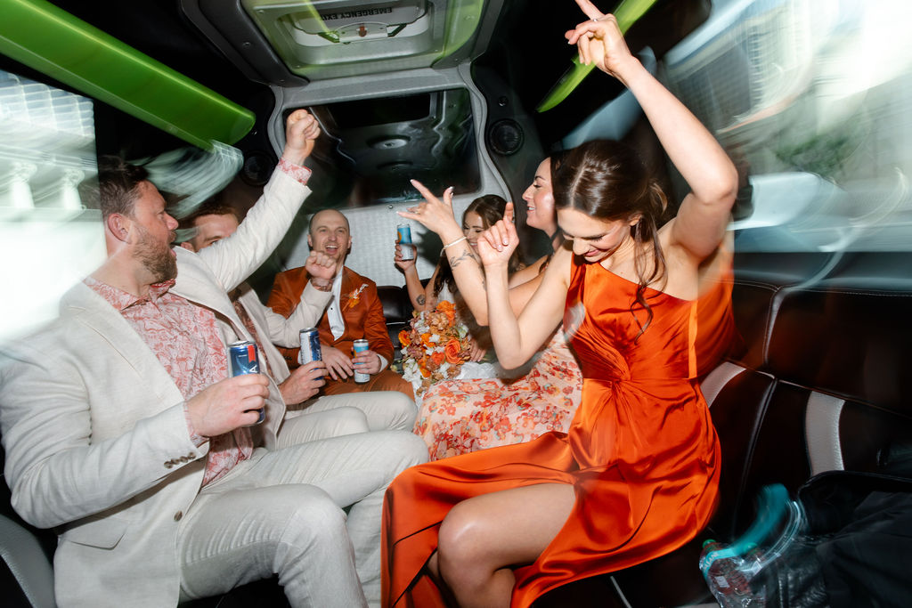 Bride and groom enjoying drinks with their wedding party on the party bus