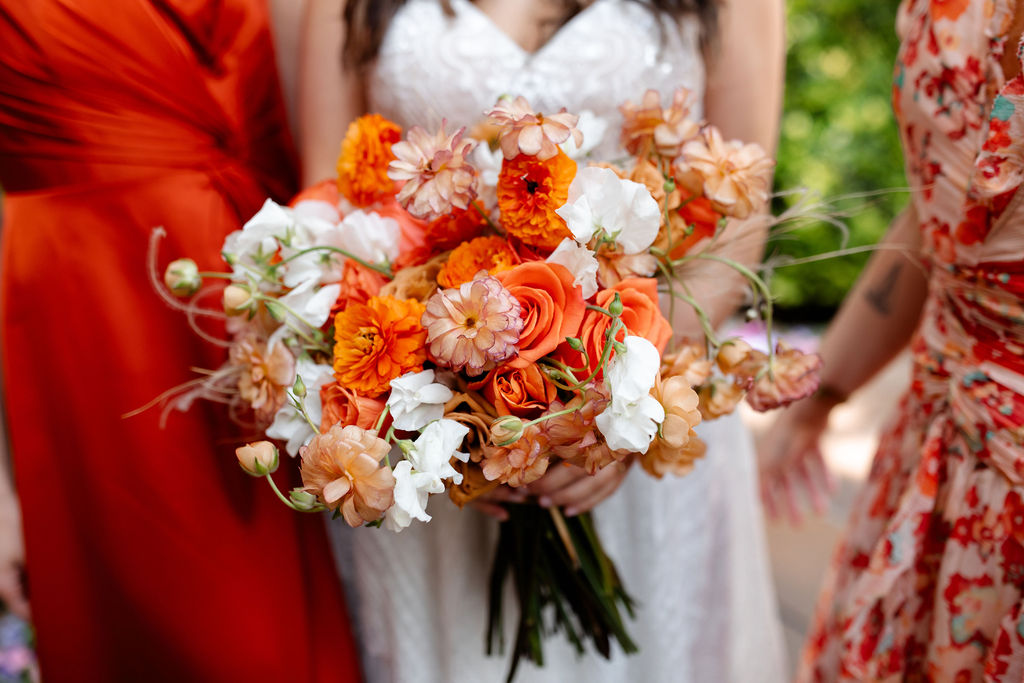 Close up shot of a bride holding a colorful spring bouquet by Mylo Fleur with her two bridesmaids 