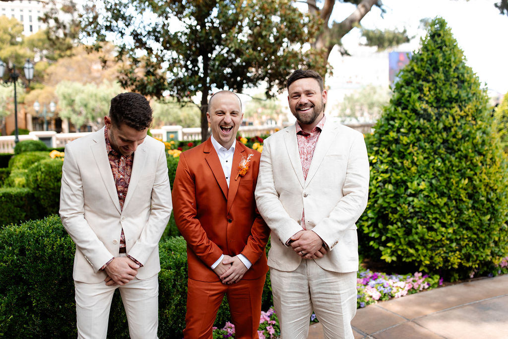 Candid groom and groomsmen photo of them laughing in the gardens of Bellagio for a Las Vegas micro wedding