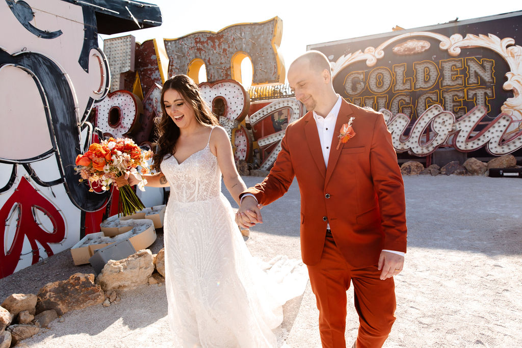 Bride and groom holding hands during their golden hour Neon Museum micro wedding in Las Vegas