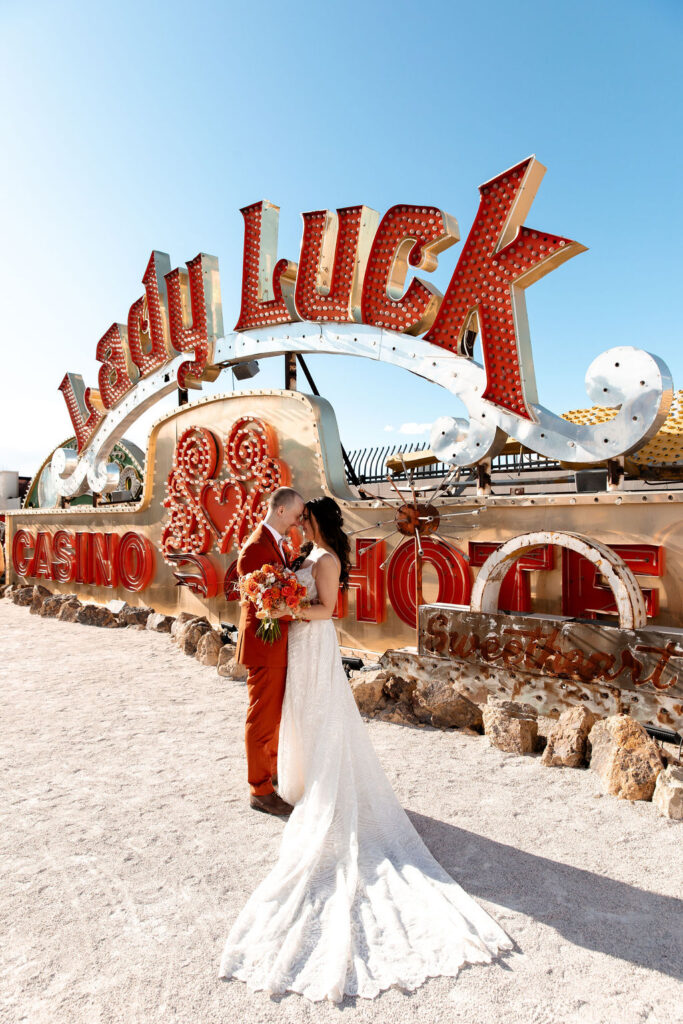Bride and groom posing next to the Lady Luck sign during their Neon Museum micro wedding