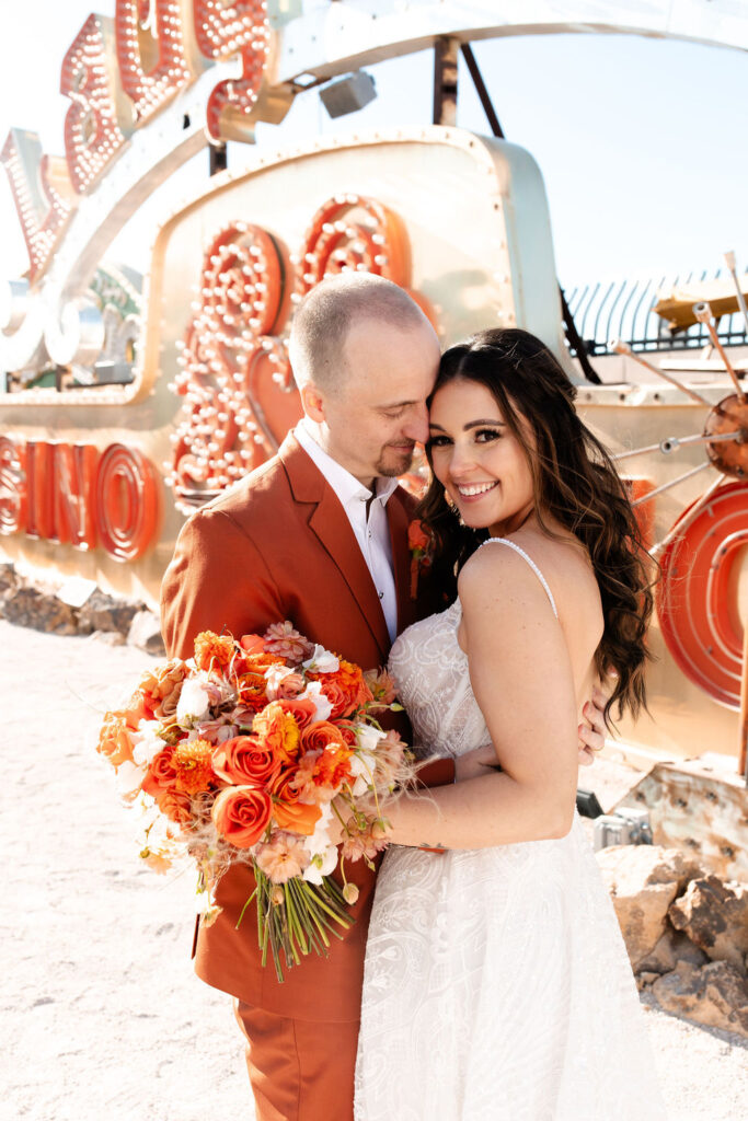 Bride and groom posing next to the Lady Luck sign during their Neon Museum micro wedding