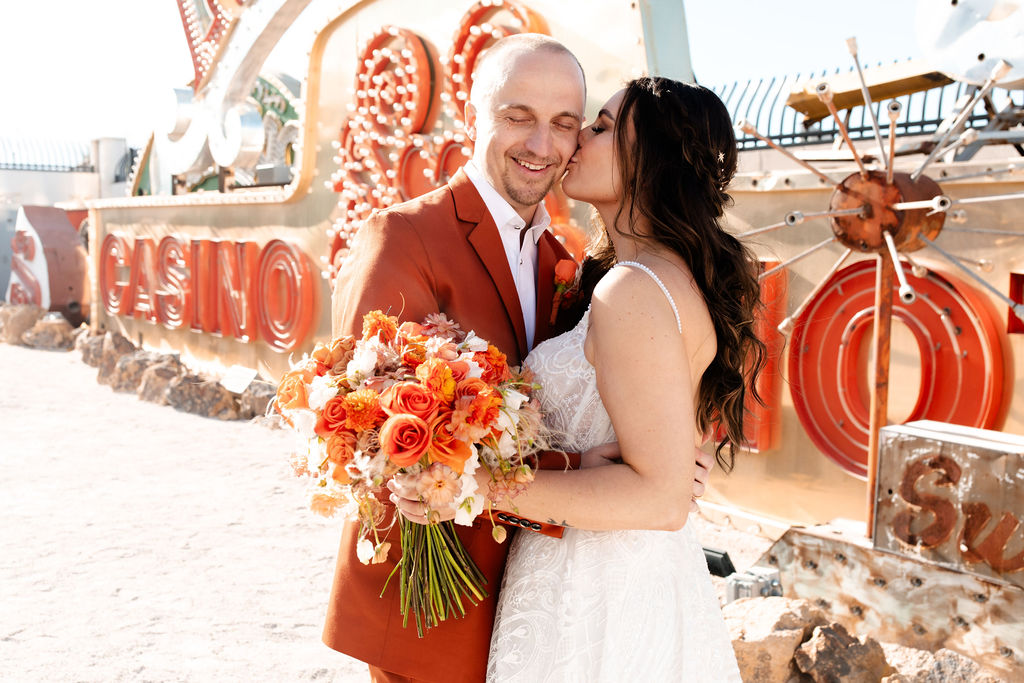 Bride kissing his grooms cheek during their Neon Museum micro wedding in Las Vegas