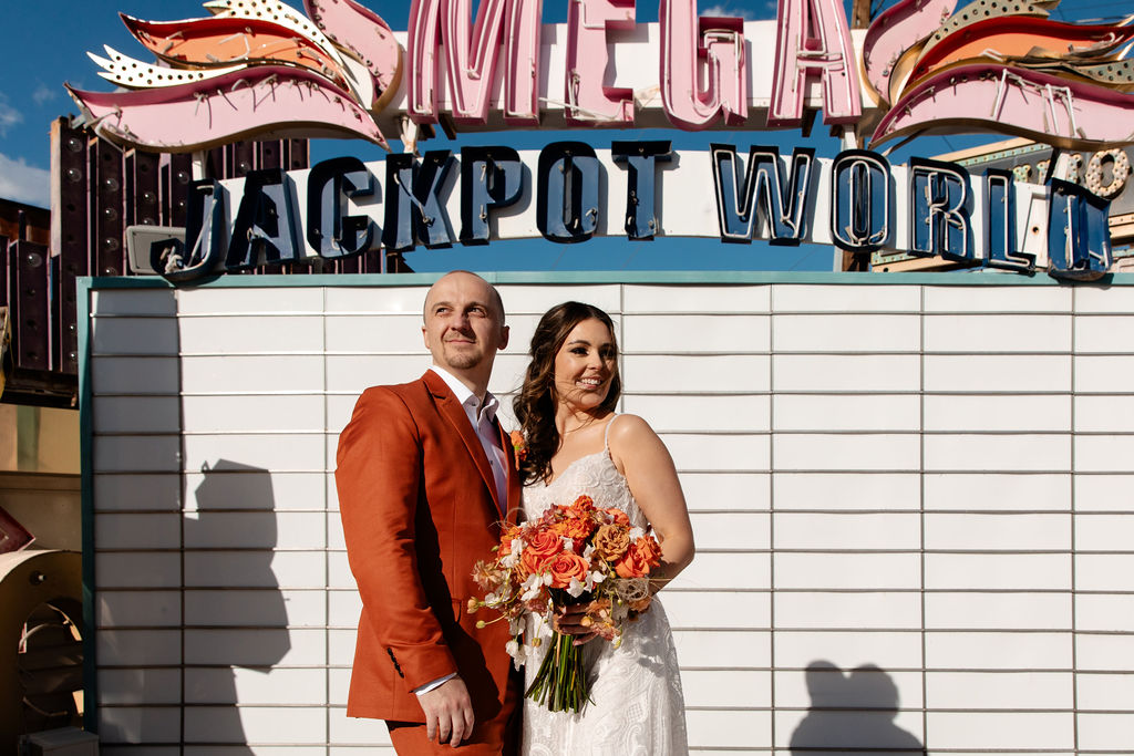 Bride and groom posing in front of the Mega Jackpot World sign at Neon Museum in Las Vegas
