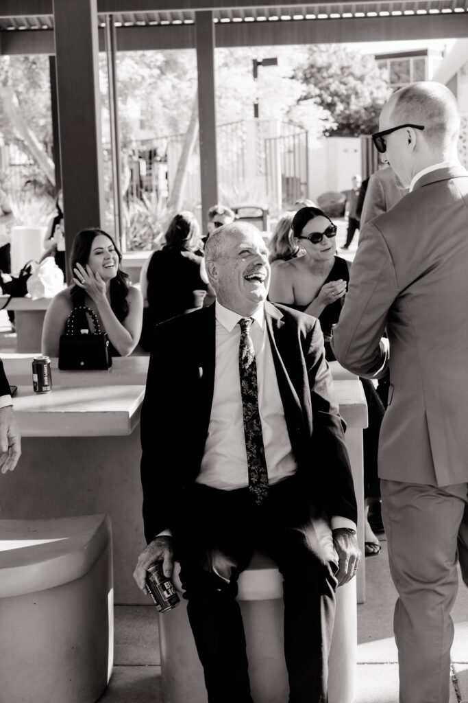 Candid black and white photo of the groom mingling with guests during cocktail hour