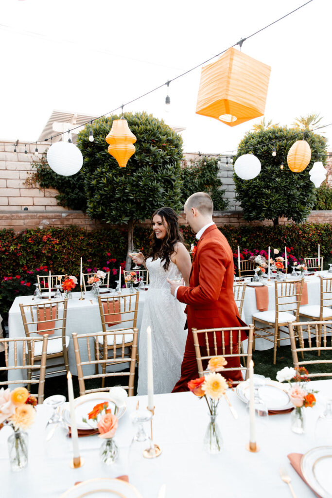 Bride and groom walking through decorated reception tables at Mid Century Manor