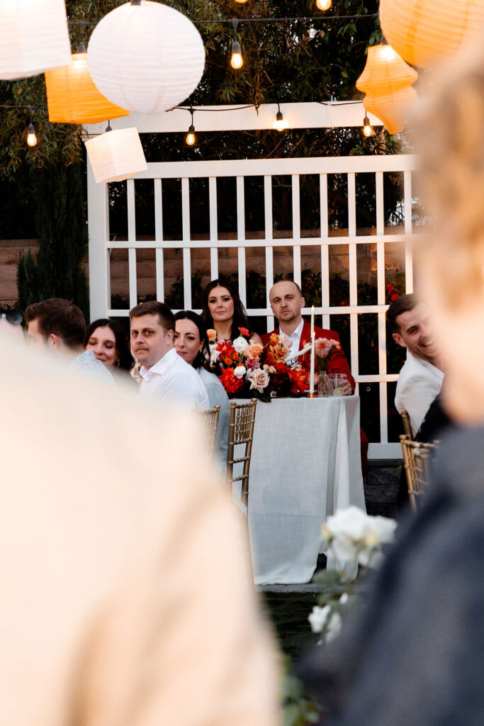 Bride and groom seated at their sweetheart table with colorful floral arrangements during their Las Vegas micro wedding reception.