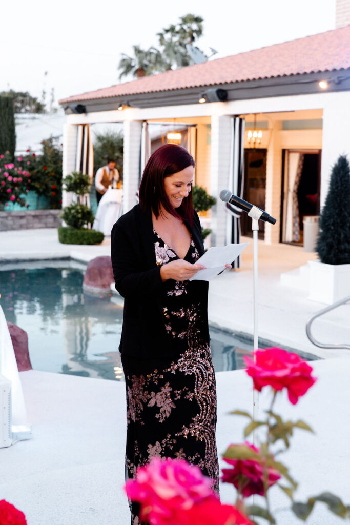 Wedding guest giving a heartfelt speech at Mid Century Manor, standing by the poolside with string lights overhead.