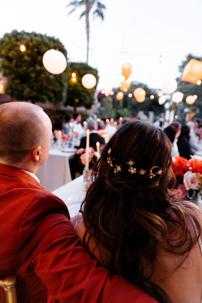 Over-the-shoulder shot of the bride and groom enjoying their Mid Century Manor Las Vegas micro wedding reception, with string lights twinkling above.