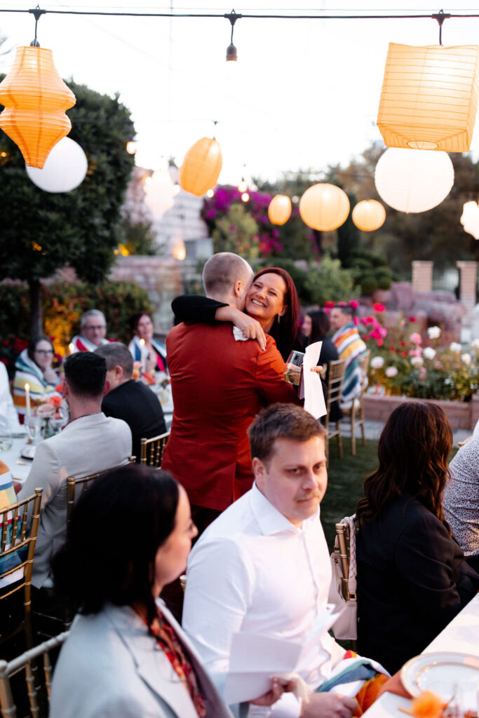 Groom embracing a guest with a big smile during speeches at the Mid Century Manor wedding reception.