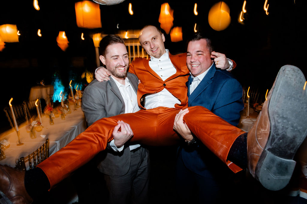 Groom being carried by two guests during his Mid Century Manor wedding reception