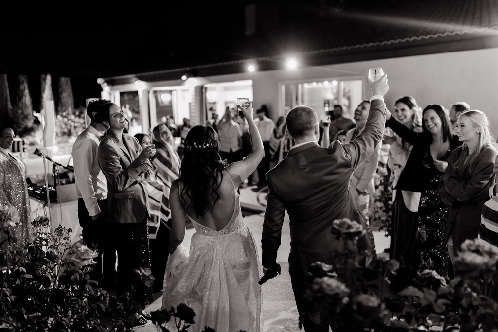 Black and white photo of a bride and groom toasting with their guests during their Mid Century Manor Las Vegas micro wedding reception