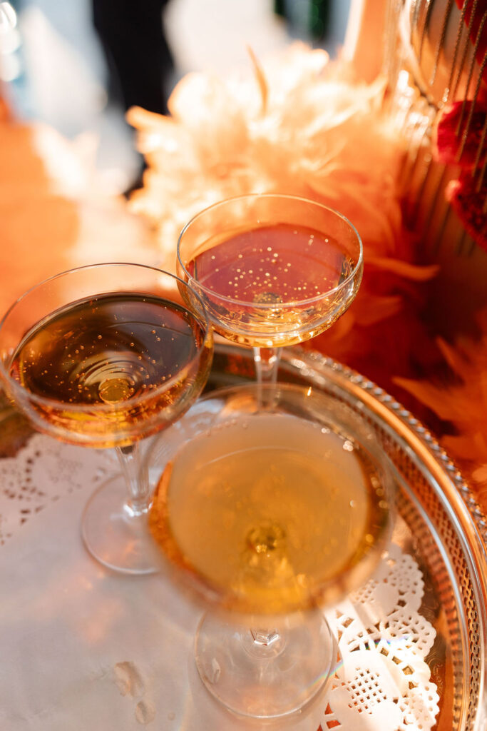 Close-up of champagne coupe glasses on a silver tray during wedding cocktail hour