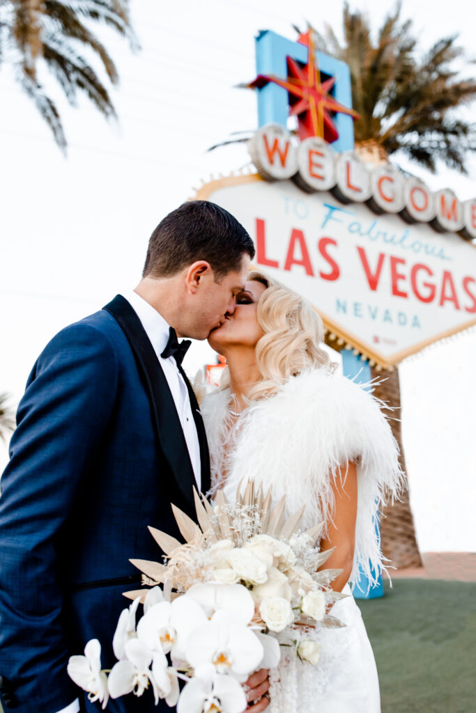 Close up shot of a bride and groom kissing in front of the Welcome to Fabulous Las Vegas sign